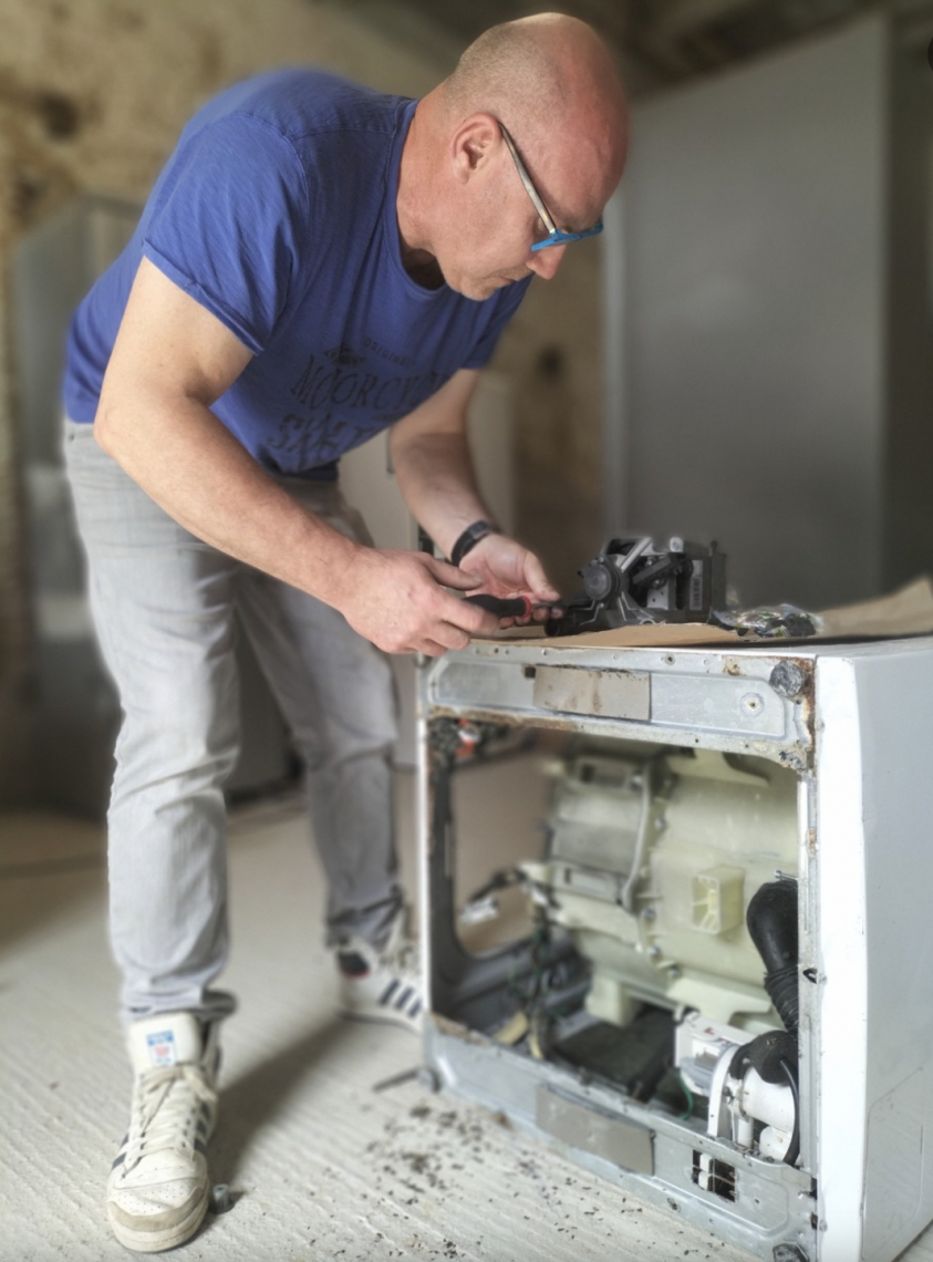 Philippe Chanez, fondateur de Thétrys / Marcel et Valentin, travaillant sur le reconditionnement d'une machine à laver. Philippe Chanez, fondateur de l'entreprise Thétrys (commercialisée sous le nom Marcel et Valentin), en train de réparer une machine à laver le linge.