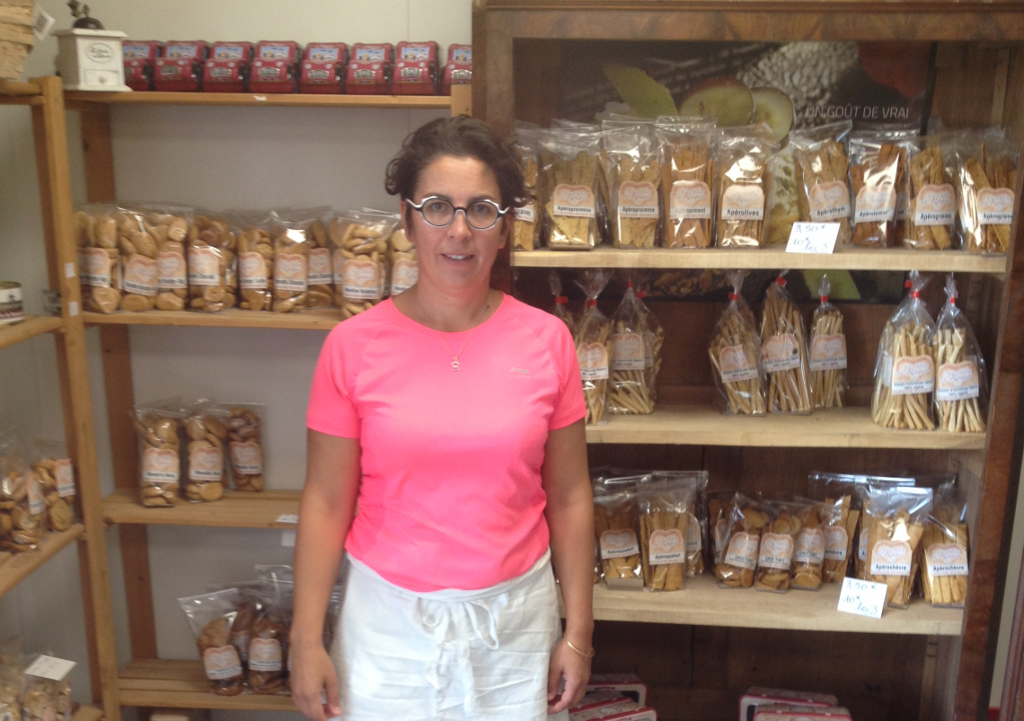 Adeline Théron, fondatrice des Délices du Rougier à Vabres-l'Abbaye, dans l'espace de vente de ses biscuits artisanaux et produits locaux. Adeline Théron, dirigeante de la biscuiterie-boulangerie Les Délices du Rougier, posant dans sa boutique à Vabres-l'Abbaye.