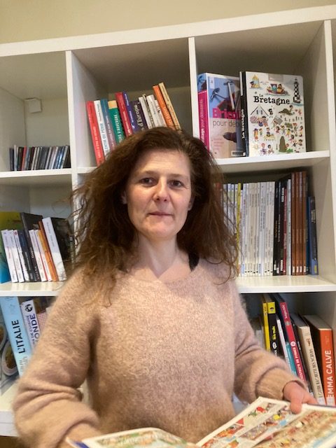 Portrait d'Aline Solignac, librairie Chemins d'Encre, devant une bibliothèque