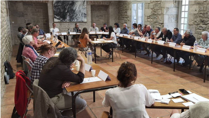 Atelier de travail collaboratif réunissant élus et techniciens dans le cadre de la préfiguration du projet de territoire QRGA avec l'Adefpat. Réunion de travail du groupe de 38 élus et techniciens de la Communauté de communes QRGA réunis autour de tables en rectangle dans une salle voûtée en pierre.