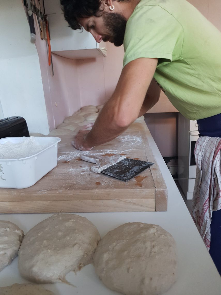 Matthieu Bodiguel en plein travail d'artisanat dans son fournil. Matthieu Bodiguel, artisan boulanger de Matt et ses pains, façonnant la pâte à la main sur son plan de travail en bois.